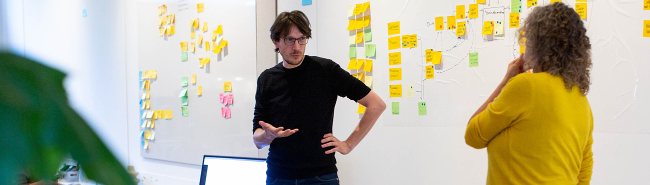 Workshop participant and moderator in action with whiteboard background.