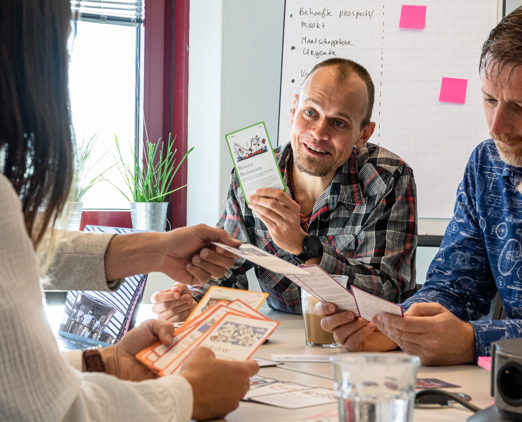 Three people in a workshop, holding cards, exchanging ideas.